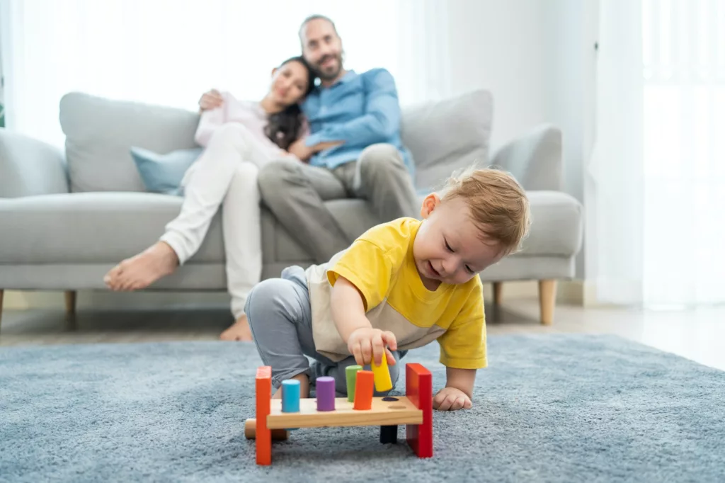 A&C Quality Cleaning LLC offers services of Residential Cleaning, Deep Cleaning, Move Out / In Cleaning in Long island, Nassau, Suffolk, Northwood - Residential Cleaning Caucasian loving parent looking at baby toddler playing in living room.
